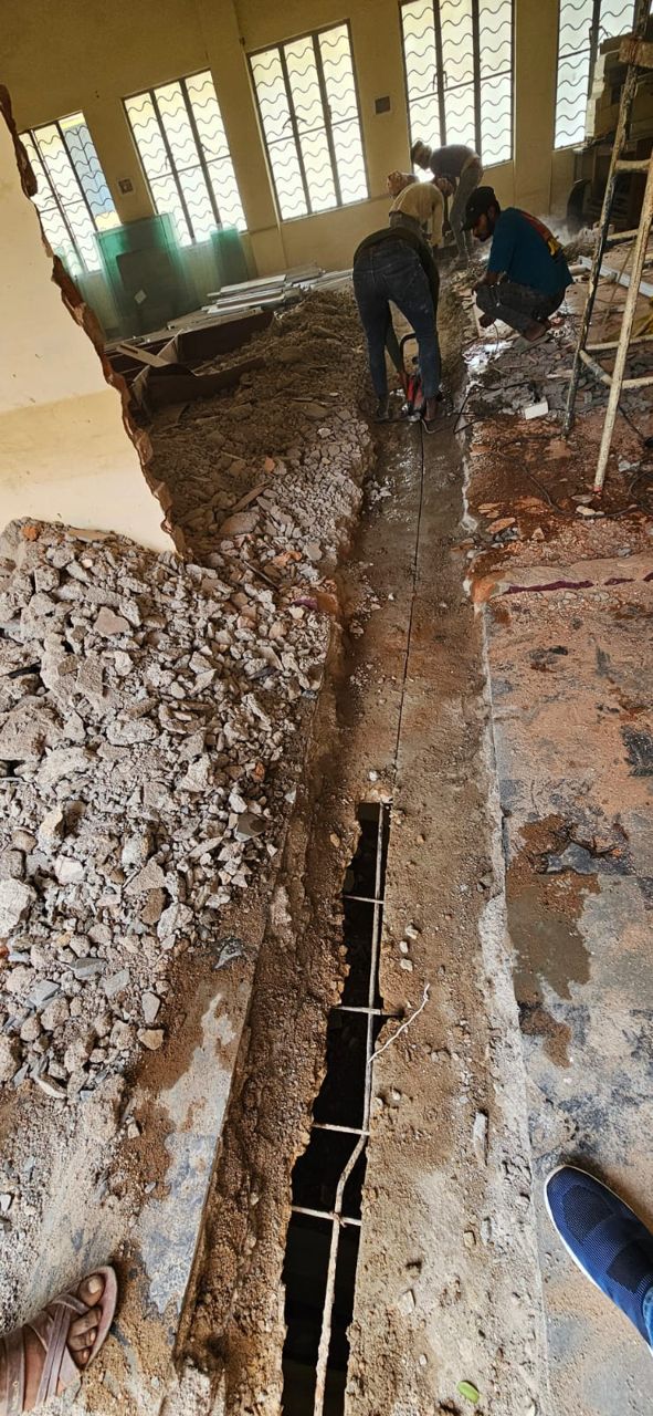 Workers cutting a trench through an indoor concrete floor