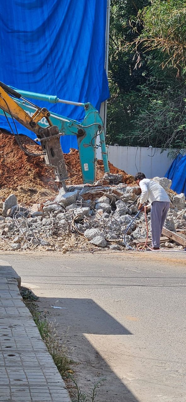 Excavator with hydraulic breaker working on concrete rubble